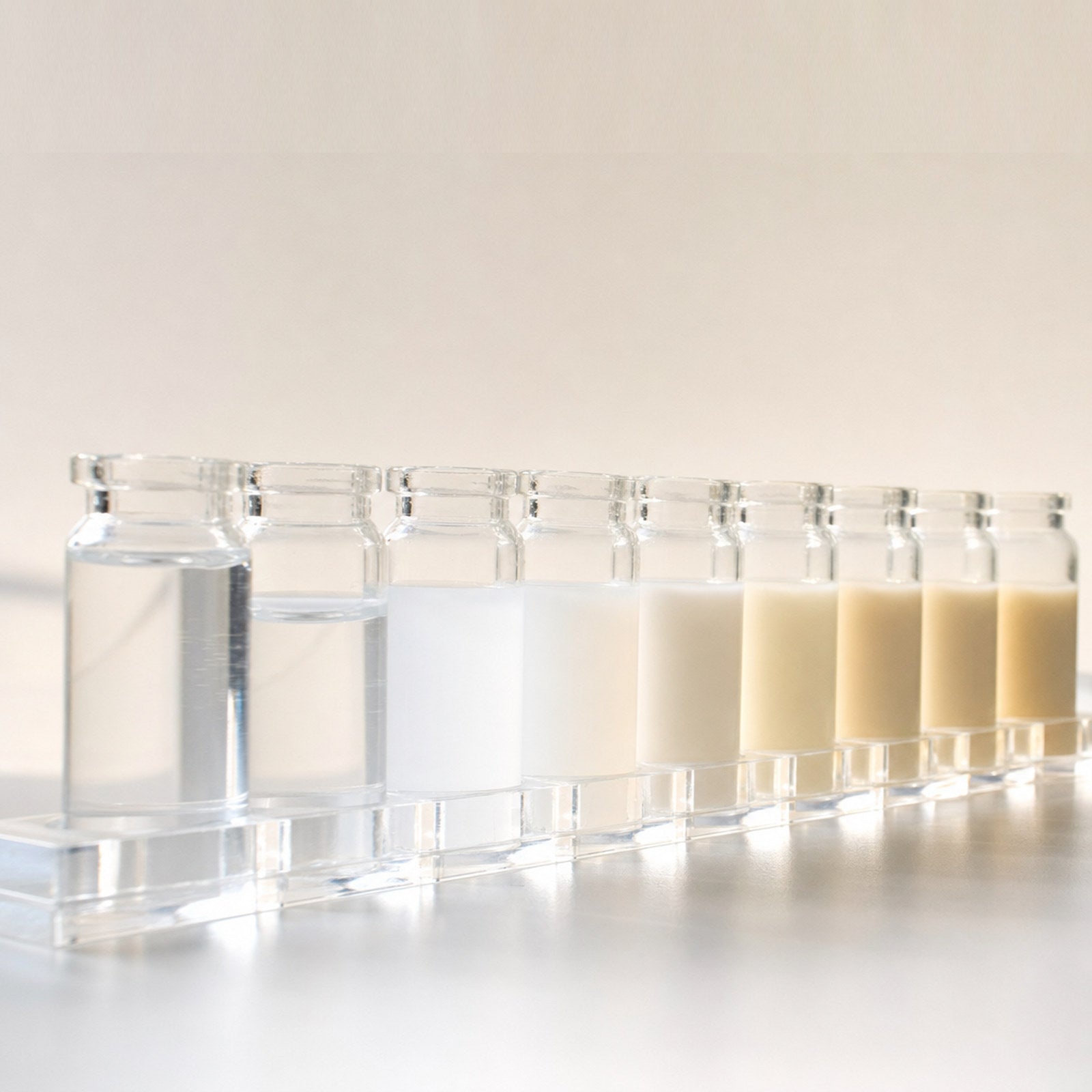 A row of glass vials, clear to milky, on a bright lab bench
